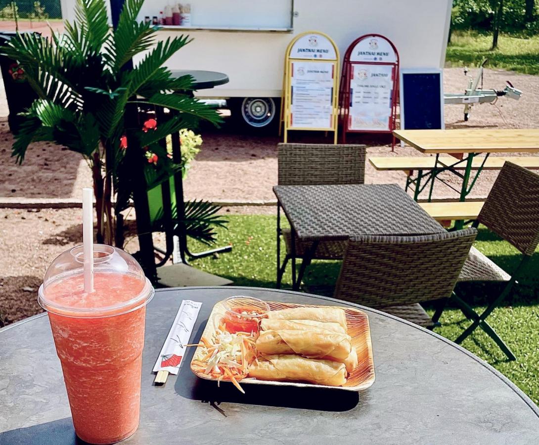 Pöydällä kaksi annosta, joista toinen kevätkääryleitä ja toinen värikäs thairuoka-annos riisillä. Pöydällä lisäksi punainen raikas smoothie.